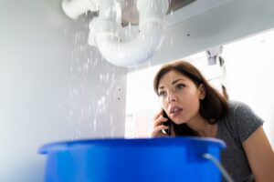 woman-calling-plumber-while-pipe-leaks